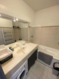 ein Badezimmer mit einem Waschbecken und einer Badewanne in der Unterkunft Résidence Pinedes Aryana - 4 Pièces pour 6 Personnes 754 in Six-Fours-les-Plages
