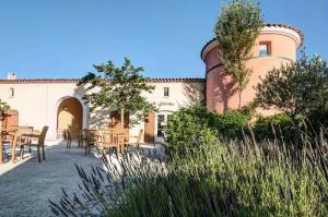 ein Gebäude mit Tischen und Stühlen davor in der Unterkunft Les maisons Le Rouret - maeva Home - Maison 3 Pièces 6 Personnes - Sélection MAE-9200 in Grospierres