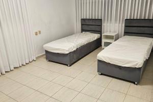 2 Betten in einem Zimmer mit weißen Fliesenböden in der Unterkunft גדולה ומעוצבת ברעננה in Ra‘ananna