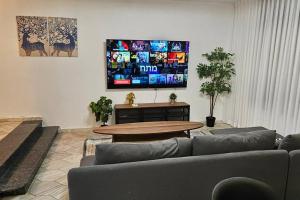 uma sala de estar com um sofá, uma mesa e uma televisão em גדולה ומעוצבת ברעננה em Ra‘ananna