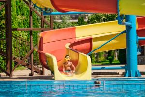 a young child on a water slide in a pool at Nessebar and Holiday Fort Apartments in Sunny Beach