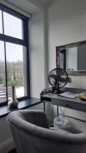 a room with a desk with a chair and a fan at The Friendship Hotel in Stocksbridge