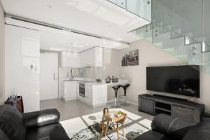 sala de estar con sofá y TV y cocina en Park Central Loft Apartment in Rosebank, en Johannesburgo