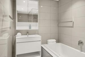 Baño blanco con bañera y lavamanos en Park Central Loft Apartment in Rosebank, en Johannesburgo
