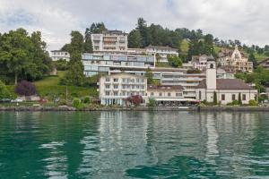 un groupe de bâtiments sur le rivage d'une masse d'eau dans l'établissement Garni-Hotel Frohburg - Beau Rivage Collection, à Weggis