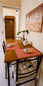 une table en bois avec deux plaques et une plante sur celle-ci, dans l'établissement Next to Metro! Bright Apartment with Fully Equipped Kitchen, à Athènes