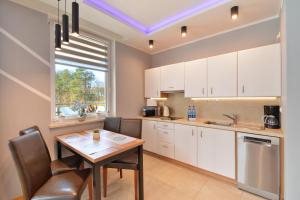 a kitchen with white cabinets and a table and chairs at Apartamenty Aquamarina SeaView by Rent like home in Międzyzdroje