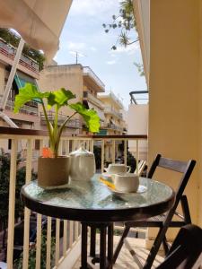 a table with two cups and a plant on a balcony at Next to Metro! Bright Apartment with Fully Equipped Kitchen in Athens