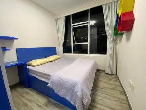 um pequeno quarto com uma cama azul e uma janela em Sora Gardens 1 em Xóm Bưng Ðìa