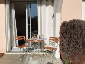 - une table et des chaises sur une terrasse couverte avec une fenêtre dans l'établissement Appartement du Cabaliros, à Argelès-Gazost