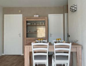 - une cuisine avec une table en bois et des chaises blanches dans l'établissement Appartement du Cabaliros, à Argelès-Gazost