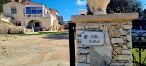 a stone wall with a sign in front of a house at Appartement Kallisté, Logements avec vue citadelle de Bonifacio in Bonifacio