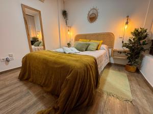 a bedroom with a large bed with a gold blanket at Suite con Cueva Romana/Roman Cave * Early Check-in in Toledo