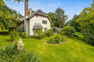 una vieja casa blanca con un patio de hierba en Ford House en Stockland