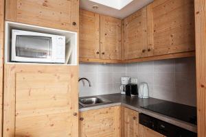 a small kitchen with a sink and a microwave at Résidence Le Christiana - maeva Home - Appartement Duplex 3 Pièces 10 Personnes - Sélection MAE-3643 in Saint-Bon-Tarentaise