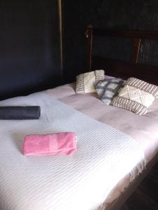 Una cama blanca con una toalla rosa. en Cabañas del mar, en Maitencillo