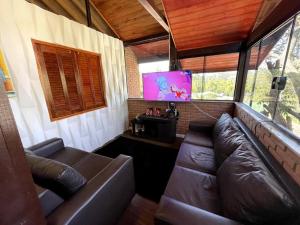 a living room with a couch and a tv at Chácara em Ibiúna com piscina e acesso a represa in Ibiúna