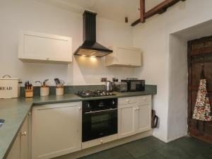 cocina con armarios blancos y fogones en Old Oak Cottage, en Ambleside