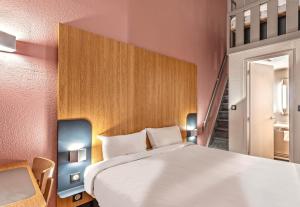 Un dormitorio con una gran cama blanca y una escalera en B&B HOTEL Quimper Nord Douarnenez en Quimper