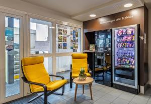 - une salle d'attente avec deux chaises et un réfrigérateur pour boissons dans l'établissement B&B HOTEL Quimper Nord Douarnenez, à Quimper