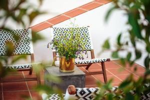 een vaas met bloemen op een tafel naast twee stoelen bij Heaven Inn Suites & Terrace in Évora