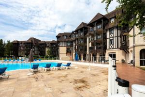 un gran complejo de apartamentos con piscina y sillas azules en La Résidence du Golf - maeva Home - Appartement 2 pièces 4 personnes - Conf 38, en Deauville