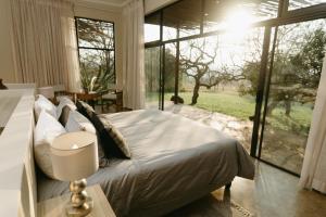 a bedroom with a bed and a large window at Sensiri Plains Safari Lodge in Mkuze
