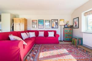 a living room with a red couch and a rug at Charming Cottage surrounded by Idyllic garden in peaceful location in central Charlbury in Charlbury