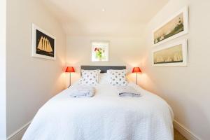 um quarto com uma cama branca e 2 candeeiros em Charming Cottage surrounded by Idyllic garden in peaceful location in central Charlbury em Charlbury