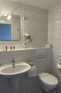 uma casa de banho com um lavatório, um WC e um espelho. em Strandhotel Dünenhaus em Juliusruh
