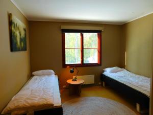 a bedroom with two beds and a table and a window at Skogsro Forest Hostel in Steinsholt