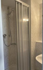 a shower with a glass door in a bathroom at Strandhotel Dünenhaus in Juliusruh