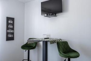 uma mesa com duas cadeiras verdes e uma televisão na parede em Penzion ob Ribniku em Podlehnik