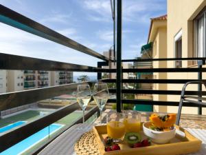 a tray of food and wine glasses on a table on a balcony at Amazing 3-bedroom apartment. Pool and sea view! in Los Cristianos