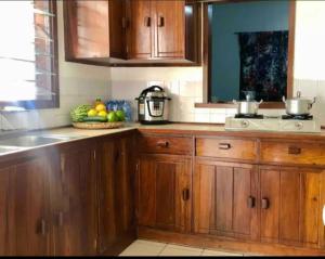a kitchen with wooden cabinets and a bowl of fruit at Mambo & Jambo Homestay in Mwanza