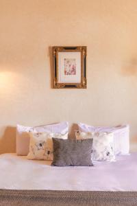 a bed with pillows and a picture on the wall at The Gardener's House, Petit déjeuner inclus in Marrakesh