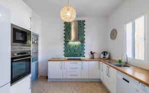 a kitchen with white cabinets and a chandelier at La casa de los marqueses in Villanueva del Ariscal