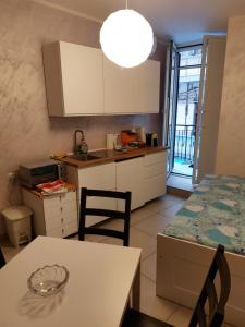 une cuisine avec des placards blancs et une table avec des chaises dans l'établissement Aglianico Guest House, à Naples
