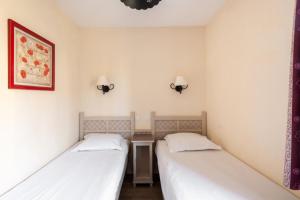 Duas camas num pequeno quarto com paredes brancas em Les Coteaux de Pont Royal en Provence - maeva Home - Maison 3 Pièces 6 Perso 13 em Mallemort