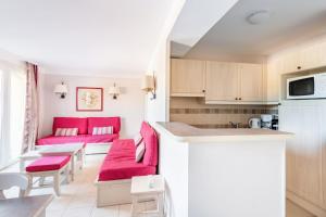 cocina y sala de estar con cojines rojos en Les Coteaux de Pont Royal en Provence - maeva Home - Maison 4 Pièces 8 Perso 14, en Mallemort