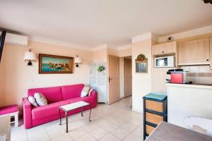 salon z różową kanapą i kuchnią w obiekcie Les Coteaux de Pont Royal en Provence - maeva Home - Appartement 2 Pièces 4 Personnes - Prestige MAE-6030 w mieście Mallemort