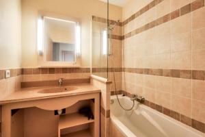 łazienka z umywalką, wanną i lustrem w obiekcie Les Coteaux de Pont Royal en Provence - maeva Home - Appartement 2 Pièces 4 Personnes - Prestige MAE-6030 w mieście Mallemort