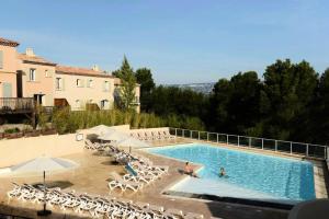 une grande piscine avec des chaises et des parasols dans l'établissement Les Coteaux de Pont Royal en Provence - maeva Home - Appartement 2 Pièces 4 16, à Mallemort