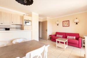 een woonkamer met een rode bank en een tafel bij Les Coteaux de Pont Royal en Provence - maeva Home - Appartement 2 Pièces 4 16 in Mallemort