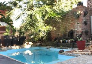 a swimming pool in a backyard with a brick wall at A La Martha's Air-Port Guest House in Port Elizabeth