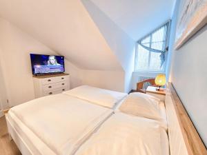 ein Schlafzimmer mit einem Bett und einem Fernseher an der Wand in der Unterkunft Dünenpark Binz - Klassik Ferienwohnung mit 1 Schlafzimmer und Balkon im Dachgeschoss 184 in Binz