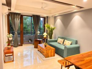 uma sala de estar com um sofá verde e uma mesa em Hotel South Ex Residency - South Ex near AIIMS Delhi - Couple Friendly em Nova Deli
