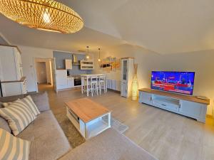 ein Wohnzimmer mit Couch und Flachbildfernseher in der Unterkunft Dünenpark Binz - Klassik Ferienwohnung mit 1 Schlafzimmer und Balkon im Dachgeschoss 184 in Binz