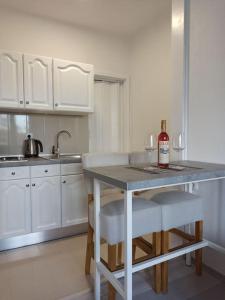 Una cocina blanca con una mesa con una botella de vino. en Apartment IVA, en Čitluk