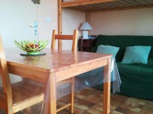 a wooden table in a living room with a green couch at Studio Vieux-Boucau-les-Bains, 1 pièce, 2 personnes - FR-1-379-32 in Vieux-Boucau-les-Bains